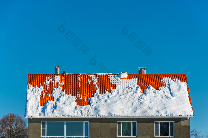 明亮的橙色屋顶覆盖与雪蓝色的天空背景