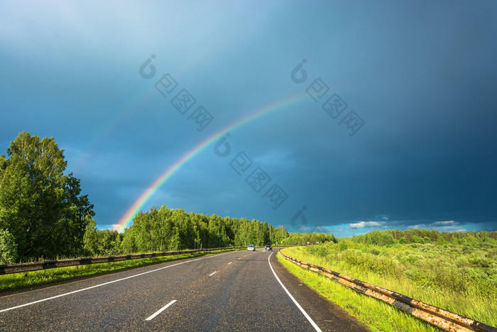 明亮的色彩斑斓的彩虹在的高速公路的背景的多云的天空