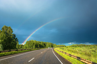 明亮的色彩斑斓的彩虹在的高速公路的背景的多云的天空