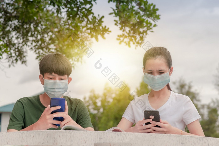 男孩和女孩脸面具新正常的使用移动聪明的电话保持社会距离保护冠状病毒科维德