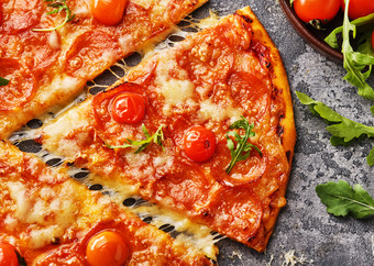 片意大利辣香肠披萨与樱桃西红柿切片美味的意大利辣香肠披萨的灰色石头背景前视图