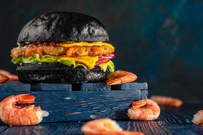 芝士汉堡与虾黑色的好木蓝色的背景黑色的汉堡与海鲜