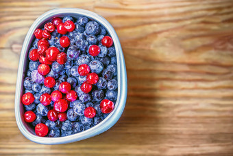 冻蓝莓和蔓越莓灰色的杯木背景特写镜头空间为复制蓝莓和蔓越莓杯