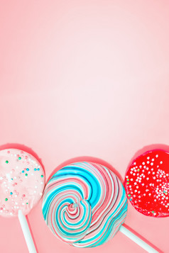 粉红色的背景与三个五颜六色的糖果复古的风格空间为复制粉红色的背景与彩色的糖果