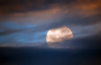 完整的月亮特写镜头后面的黑暗云出焦点的晚上天空完整的月亮后面云