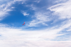红色的回飞棒苍蝇的蓝色的天空在纯白色云红色的回飞棒飞行