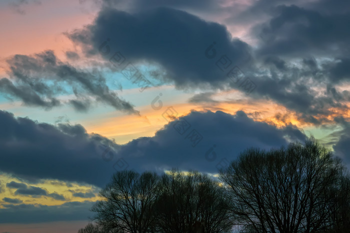 大黑暗云的背景色彩斑斓的日落天空在轮廓树色彩斑斓的云的晚上天空