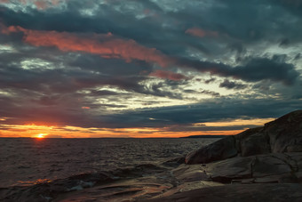 日落的多云的天空在石头海滨之前风暴晚上景观之前的风暴海