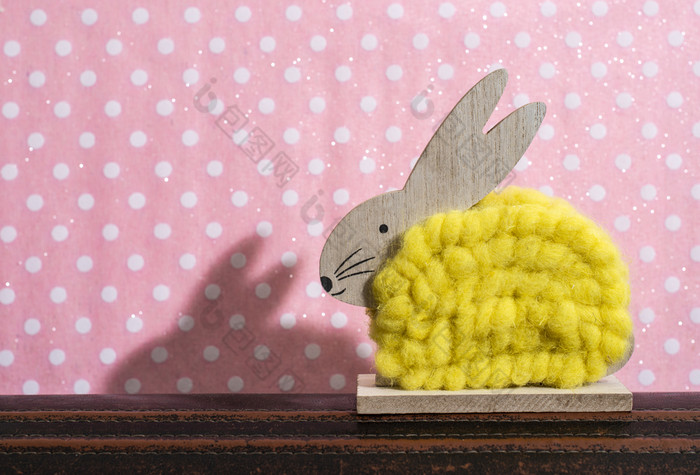 黄色的复活节兔子前面墙点房间兔子装饰和粉红色的壁纸背景点影子兔子的墙木兔子数字形状和黄色的纱极简主义概念