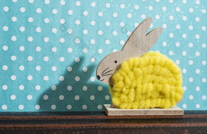 黄色的复活节兔子前面墙点房间兔子装饰和蓝色的壁纸背景点影子兔子的墙木兔子数字形状和黄色的纱极简主义概念