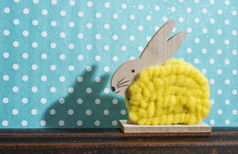 黄色的复活节兔子前面墙点房间兔子装饰和蓝色的壁纸背景点影子兔子的墙木兔子数字形状和黄色的纱极简主义概念