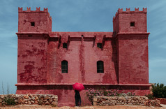 年轻的孤独的女人与红色的伞保护你自己从的太阳下一个红色的古老的城堡
