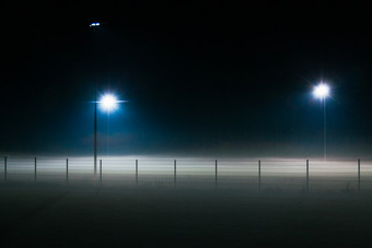 孤独的<strong>足球场</strong>覆盖雾晚上只有照亮聚光灯
