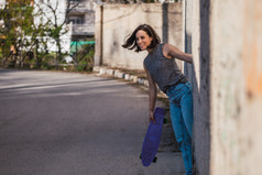 年轻的女人与蓝色的一分钱滑板休闲穿抓住古老的金属工业通过自由概念