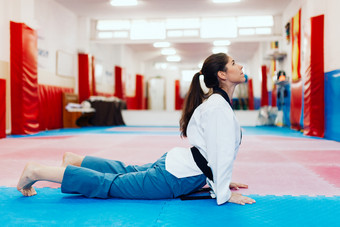 年轻的女人伸展运动dojo穿跆拳道西装