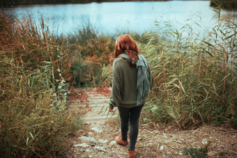年轻的红色头发的人女人走的湖<strong>海岸</strong>与耳机穿<strong>泽西</strong>岛和黑色的牛仔裤