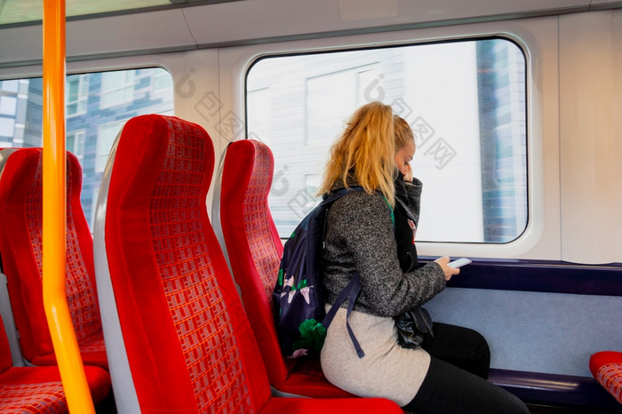 女人与卫生脸面具保持安全距离的座位火车因为的冠状病毒