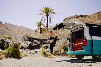 年轻的活跃的女人练习瑜伽沙漠阳光明媚的一天健康和活跃的生活概念与郎普年轻的活跃的女人练习瑜伽沙漠阳光明媚的一天与郎普