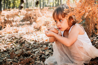 小高加索人婴儿女孩蹲的森林在蕨类植物戏剧与植物小高加索人婴儿女孩蹲的森林在蕨类植物