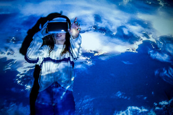 女人使用虚拟现实耳机移动手互动技术展览与多色投影仪光照明身临其境的概念