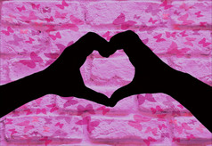 情人节一天背景轮廓两个手使心形状在一起孤立的粉红色的砖墙与蝴蝶rsquo