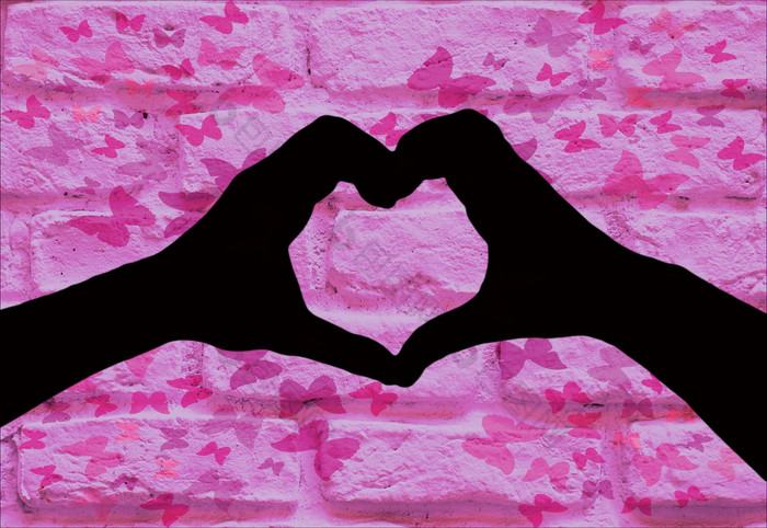 情人节一天背景轮廓两个手使心形状在一起孤立的粉红色的砖墙与蝴蝶rsquo