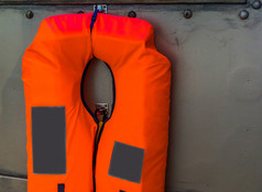 典型的橙色生活夹克挂金属墙水运输安全海洋背景