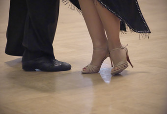 水平特写镜头两个无法辨认的舞者的鞋子壮举和腿他们的阿根廷探戈跳舞地板上在跳舞学院竞争行动拍摄的专业舞者探戈