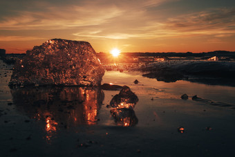 块美丽的透明的冰粉红色的和<strong>琥珀</strong>色的颜色<strong>珠宝</strong>闪亮的冻海滨的日落