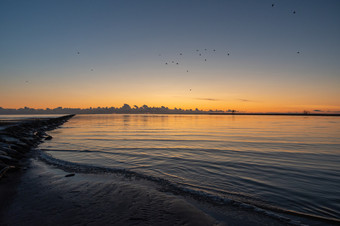 日落在摩尔帕努着色水波罗的海海橙色蓝色的和黄色的鸟看塔地平线<strong>群鸟飞行</strong>的天空