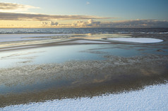 日出光在的雪海滩波罗的海海冬天早....与的美丽的反射云水