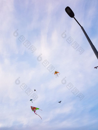 色彩斑斓的风筝飞行对天空和灯帖子对角形成