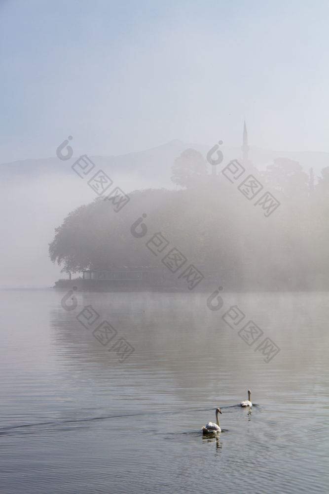 大气场景两个天鹅湖潘沃蒂斯有雾的早....约希腊与狮子帕夏清真寺的背景