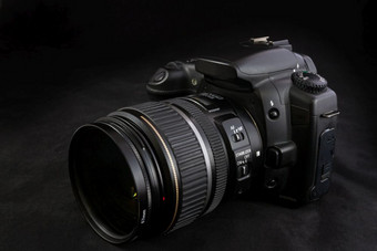 一个黑色的数码单反相机相机孤立的黑色的背景与安装变焦镜头
