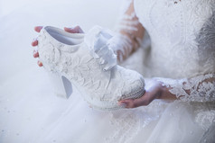 的新娘持有白色花边新娘鞋她的手