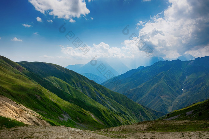田园夏天景观与徒步旅行小道的山与美丽的新鲜的绿色山牧场蓝色的天空和云tian-shan吉尔吉斯斯坦田园夏天景观与徒步旅行小道的山与美丽的新鲜的绿色山牧场