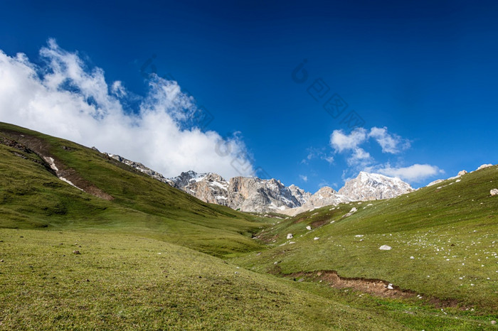 田园夏天景观与徒步旅行小道的山与美丽的新鲜的绿色山牧场蓝色的天空和云tian-shan吉尔吉斯斯坦田园夏天景观与徒步旅行小道的山与美丽的新鲜的绿色山牧场