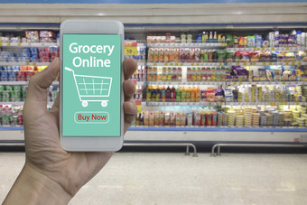 手使用智能手机与杂货店在线屏幕在模糊超市和零售商店购物购物中心室内背景