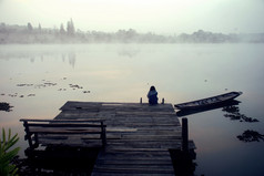 安静的冬天女孩坐着独自一人看的河在那里是静止的木船美丽的合适的为背景图片