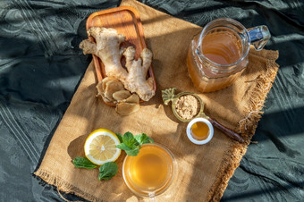 热姜汁与柠檬和薄荷根和片姜服务与棕色（的）糖和蜂蜜麻布背景热姜汁可以帮助气候变暖身体健康的喝