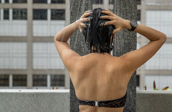 短头发的年轻的女人黑色的比基尼取淋浴之前和后游泳池和黑色的比基尼时尚夏天季节