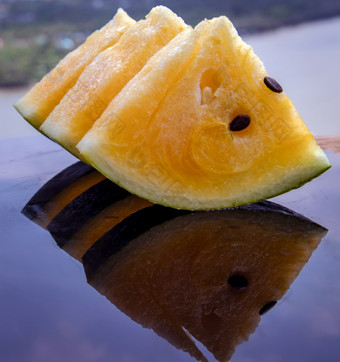 新鲜的多汁的黄色的西瓜减少成三角形黑色的丙烯酸表与反射和自然视图热带水果复制空间选择焦点