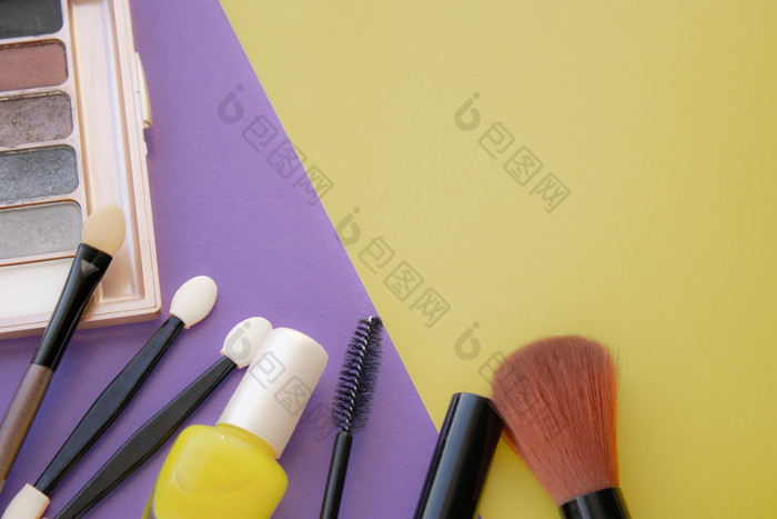 化妆品配件刷为脸红刷清漆黄色的紫色的背景与空空间的正确的视图从以上化妆品配件刷为脸红刷清漆黄色的紫色的背景