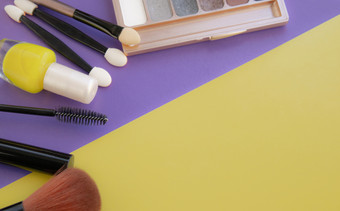 化妆品配件刷为脸红刷清漆黄色的紫色的背景与空空间的正确的视图从以上化妆品配件刷为脸红刷清漆黄色的紫色的背景