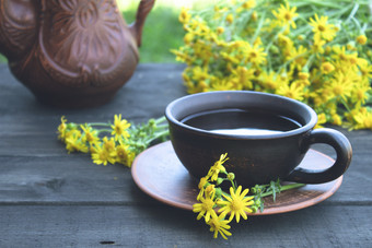 茶壶和杯茶站木蓝色的董事会与黄色的黛西花特写镜头茶壶和杯茶站木老董事会与黄色的黛西花与复制空间