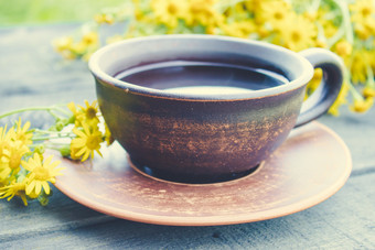 杯茶从黄色的雏菊与花束雏菊木背景特写镜头杯茶从黄色的雏菊与花束雏菊木背景