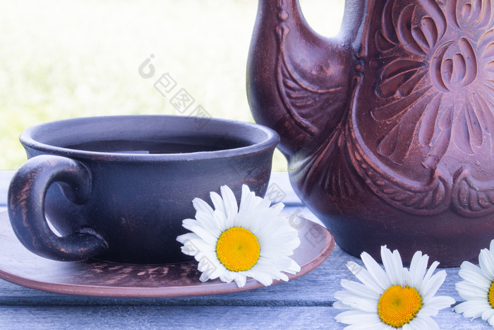茶壶和杯茶站木蓝色的董事会与黛西花特写镜头茶壶和杯茶站木蓝色的董事会与黛西花