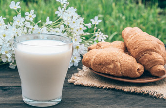 玻璃杯牛奶站旁边羊角面包和白色小花下一个的羊角面包和白色花玻璃杯牛奶