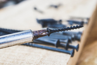钢螺杆把螺丝刀木董事会背景的概念工具和修复工作钢螺丝金属螺杆钢螺杆把螺丝刀木董事会背景的概念工具和修复工作钢螺丝