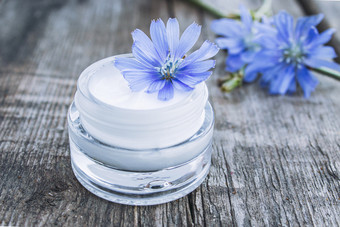 蓝色的菊苣花和脸奶油玻璃Jar老木表格健康概念水疗中心蓝色的菊苣花和脸奶油玻璃Jar老木表格健康概念
